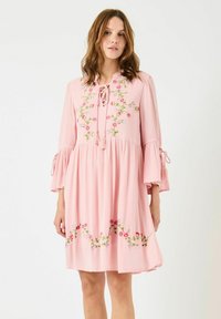 Abito rosa realizzato in tessuto leggero, caratterizzato da ricami floreali, una scollatura con fiocco e maniche a campana con legature laterali.