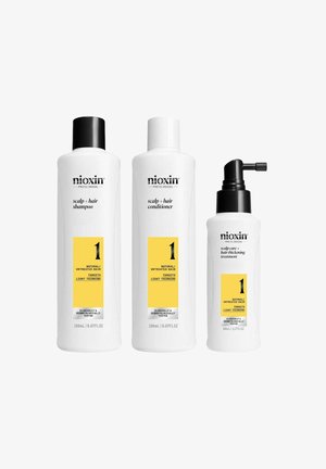 Drie Nioxin haarverzorgingsproducten: een witte shampoofles met een zwarte dop, een witte conditionerfles en een behandelfles met een zwarte pomp.