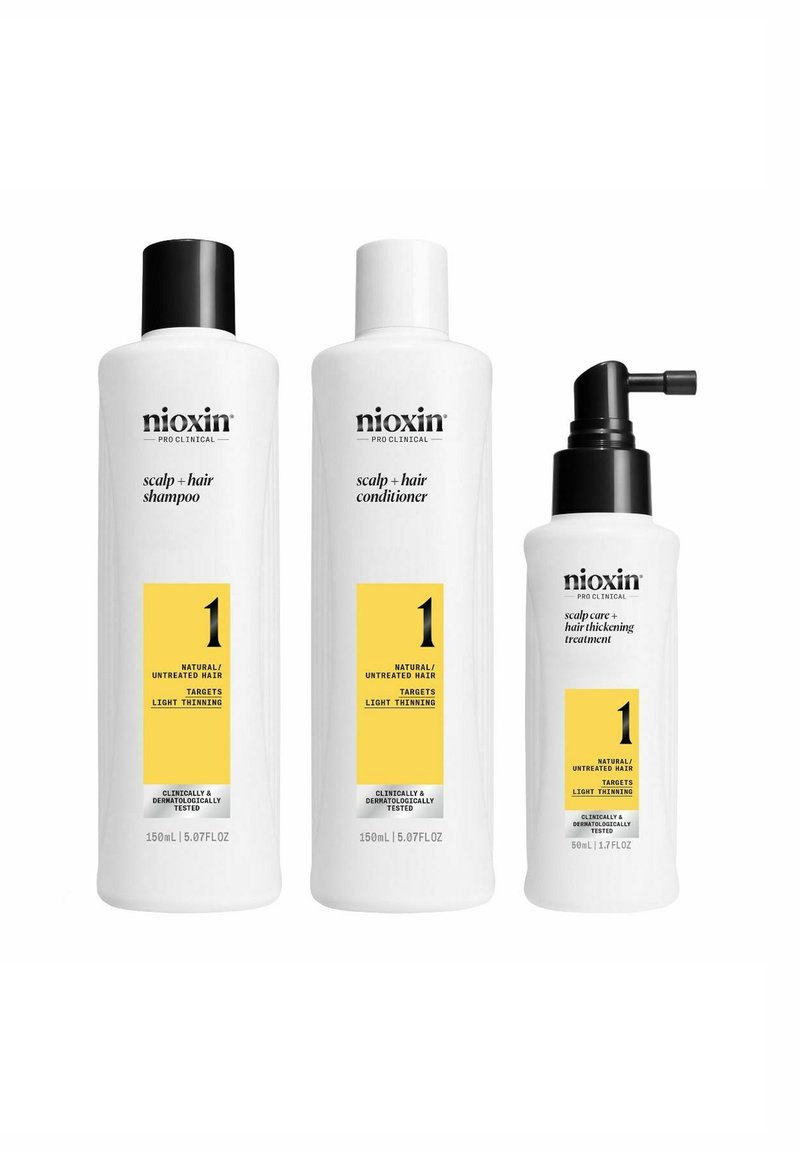 Drie Nioxin haarverzorgingsproducten: een witte shampoofles met een zwarte dop, een witte conditionerfles en een behandelfles met een zwarte pomp.