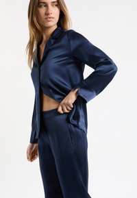 Granatowy satynowy zestaw dwuczęściowy z koszulą na guziki z kołnierzem oraz spodniami z elastycznym pasem, prezentujący gładką fakturę.