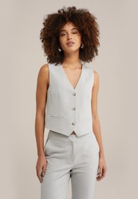 Gilet senza maniche grigio chiaro con scollatura a V, cinque bottoni e due tasche frontali. Tessuto liscio, vestibilità sartoriale, design strutturato.