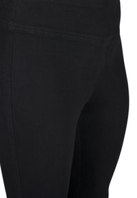 Leggings negros con una tela elástica y suave, con una cintura alta y un sutil detalle de costura a lo largo de los lados.