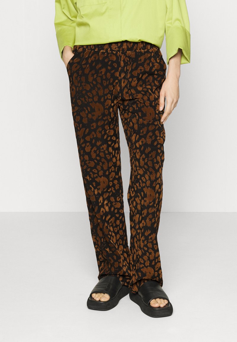 Schwarz-braune Leopardenmuster-Hosen mit lockerer Passform und elastischem Bund. Tragen mit schwarzen Riemchensandalen.