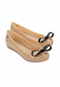 Ballerine patent in tonal nude con un accento in nero sul puntale, design open toe, texture liscia e un leggero tacco a zeppa.