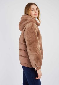 Brązowa pikowana kurtka z pluszowym wykończeniem i dopasowanym krojem, wyposażona w kaptur, ściągacze na rękawach oraz gładką fakturę. Widok z boku.
