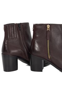 Burgundy leather ankle boots with a block heel, featuring a side zipper and vertical stitching detail on the rear. Smooth texture.