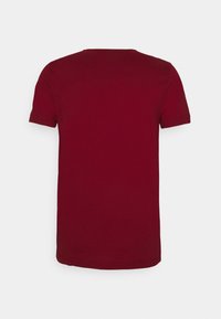 Bordeaux kortærmet t-shirt lavet af bomuld med rund halsudskæring og en glat tekstur, der har et enkelt, ensfarvet design.