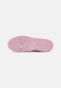 Nike cipő rózsaszín gumi talppal, körkörös és vonalas mintázattal. Simább felület és dombornyomott logó részlet a közepén.