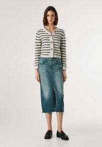 Gebreide cardigan met marineblauwe strepen, knoopsluitingen en een V-hals; lichtblauwe denimrok met een voorkapsluiting, gecombineerd met zwarte loafers.