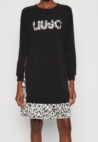 Schwarzes Sweatshirtkleid mit einem Stufenrock im Leopardenmuster. Das Oberteil hat lange Ärmel und einen runden Halsausschnitt mit „LIU-JO“-Logo-Details.
