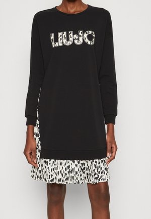 Robe sweat noire présentant une jupe à volants à imprimé léopard. Le haut a des manches longues et un col rond avec des détails du logo "LIU-JO".