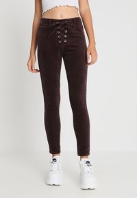 Bruna ribbade skinny-byxor med snörning fram, silverfärgade öglor och en mjuk textur, i kombination med vita platåskor.