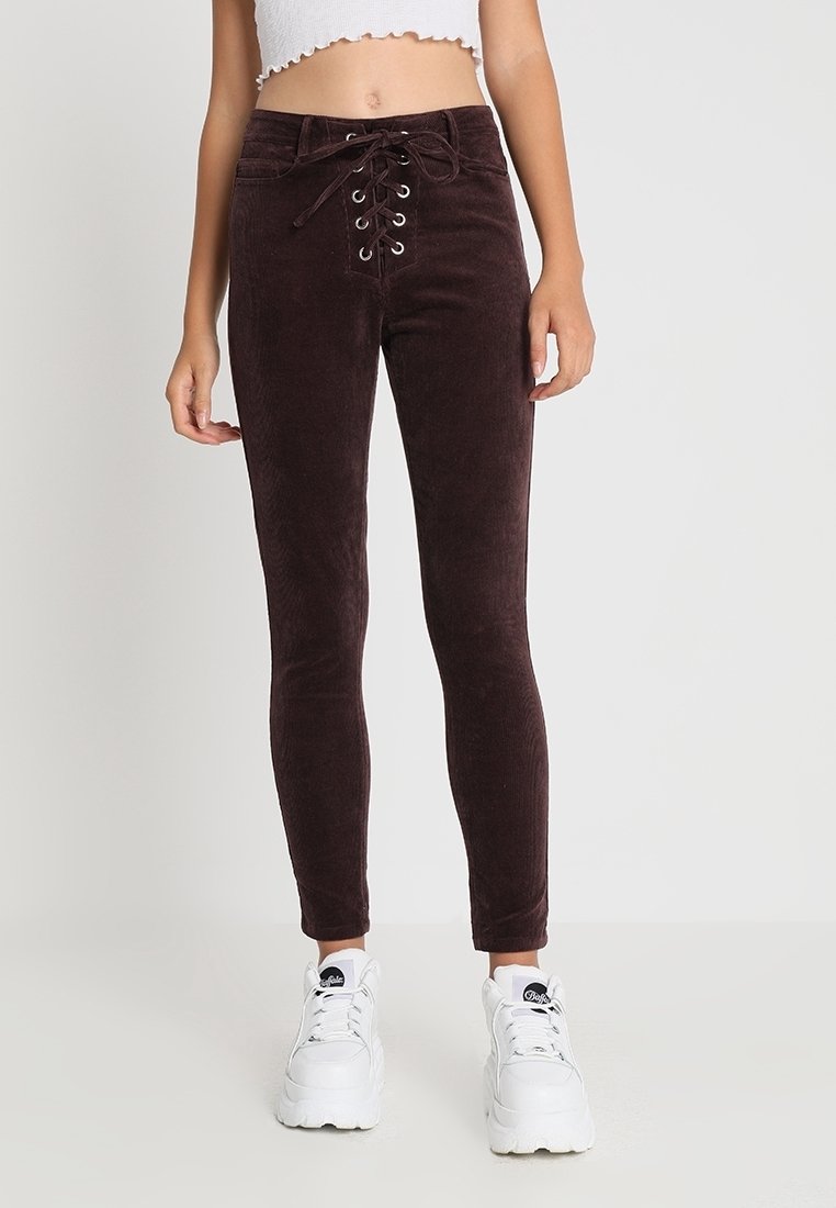 Bruna ribbade skinny-byxor med snörning fram, silverfärgade öglor och en mjuk textur, i kombination med vita platåskor.