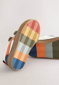 Baskets avec une semelle en caoutchouc présentant un motif chevrons multicolore en rouge, orange, bleu, jaune et vert ; tige en toile et fermetures à velcro.