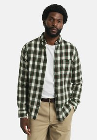 Geruite flanellen shirt in groen en wit met accenten in rood en blauw. Voorzien van een knoopsluiting aan de voorkant, een kraag en een borstzak. Lichtgewicht materiaal.