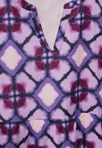 Lila gemusterter Stoff mit einem Diamantmotiv in Rosa- und Dunkellila-Tönen, ausgestattet mit einem V-Ausschnitt und gerafftem Nahtdetail.