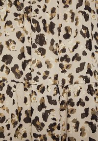 Tissu à imprimé léopard présentant des nuances de marron, beige et noir, avec une finition douce et texturée et des détails froncés.