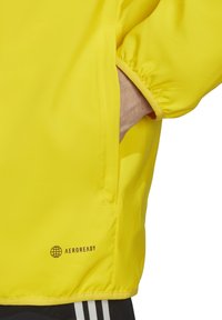 Felgeel sportjack met elastische manchetten, zijzak en "AEROREADY" logo aan de zoom. Glad, lichtgewicht stof.