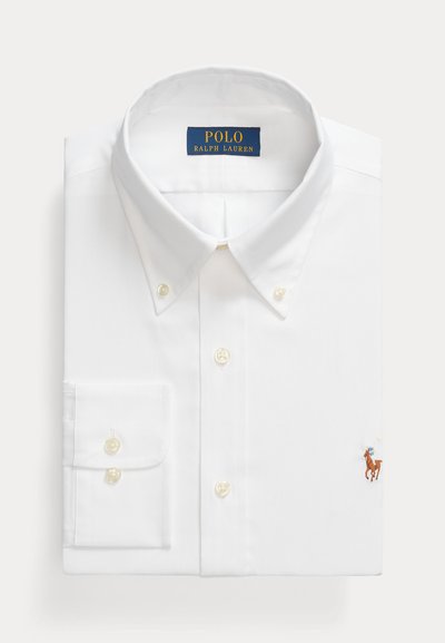Chemise blanche à manches longues avec un col classique, dotée d'une poche poitrine gauche et d'un petit logo brodé. Faite en tissu lisse.