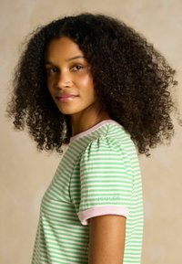 Green and white striped shirt with short sleeves, featuring a pink ribbed collar and pink trim. "JOULES" embroidered in green on the sleeve.