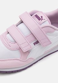 Różowo-białe sneakersy z rzepami, wykonane z teksturowanej skóry i siateczkowych materiałów, z fioletowymi akcentami i charakterystycznym logo Puma w pobliżu języka.