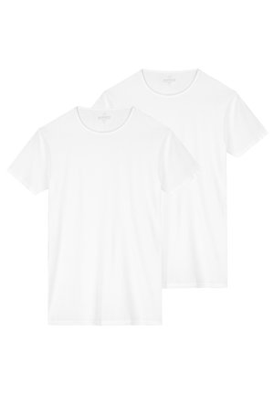 Dve bele kratke majice s kratkimi rokavi iz bombaža z okroglim izrezom, gladko teksturo in brez vidnih vzorcev ali dekoracij.