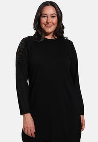 Black knit sweater dress featuring long sleeves, ribbed hem, and embellished shoulders with small metallic studs.