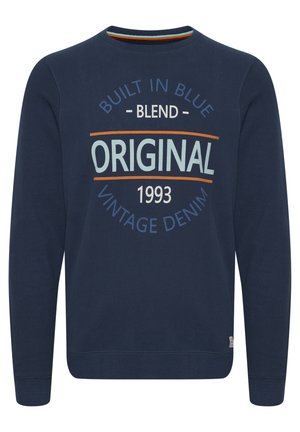 Hanorac bleumarin dintr-un amestec de bumbac, cu guler rotund, având imprimeu: "CONSTRUIT ÎN ALBASTRU," "ORIGINAL," "DENIM VINTAJ," și anul "1993."