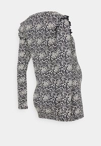 Upravený těhotenský top s dlouhým rukávem, černým pozadím a drobným bílým květinovým vzorem, se volánkovými detaily na ramenou.