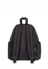 Mochila negra de tela con correas acolchadas, asa superior, bolsillos laterales y un compartimento con cremallera en la parte posterior. Textura suave y diseño sencillo.