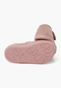 Zapato de ante rosa con suela de goma, que presenta un patrón de agarre texturizado. La suela tiene formas de huellas de patas en relieve e incluye el texto "Hecho en España".