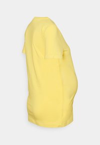 Camiseta de maternidade amarela, mangas curtas, decote redondo, feita de algodão suave, apresentando um corte descontraído para acomodar uma barriga em crescimento.