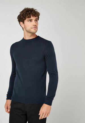 Granatowy sweter dzianinowy z okrągłym dekoltem, długimi rękawami, ściągaczami u dołu rękawów oraz na dolnym brzegu. Wykonany z miękkiej, gładkiej tkaniny.