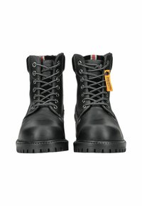 Botas de trabajo de cuero negro con ojales plateados, cordones grises y suelas de goma negra. Presenta un acento rojo y gris en el cuello y una etiqueta.