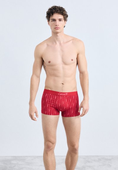 Rode boxershorts met een patroon van herhalende witte handgeschreven tekst waarop 'love' staat. Voorzien van een elastische tailleband met een contrasterend logo.