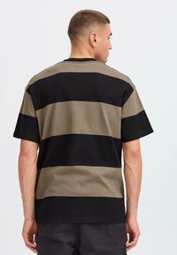 T-shirt rayé noir et vert olive, coupe décontractée, manches courtes et encolure ronde, fabriqué en coton doux.