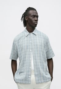Kortermig overhemd met knopen in lichtblauw met een geruit patroon, gemaakt van gestructureerde stof, voorzien van een kraag en witte knopen.