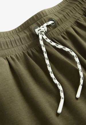 Olivgrüne Shorts mit einem elastischen Bund, ausgestattet mit einem weißen Kordelzug mit schwarzen Akzenten und einem glatten, leicht strukturierten Stoff.