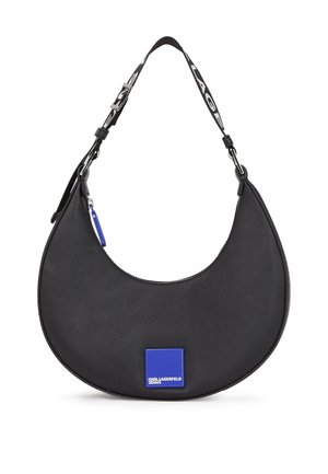 Musta, puolikuun muotoinen käsilaukku, jossa on leveä musta hihna, jossa valkoista tekstiä, ja sininen neliönmuotoinen logoplaatta, jossa lukee "Karl Lagerfeld Jeans".