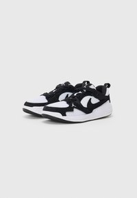 Crne i bijele atletske cipele od mrežaste i nubuk kože, s vidljivim crnim swoosh logom, vezicama i usklađenim tabanom na peti.