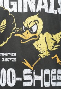 Επιθετική κίτρινη καρτουνίστικη πάπια που τρέχει με σφιχτό ράμφος, λευκό και κίτρινο κείμενο σε κατάσταση έντασης σε σκουρόχρωμο υφασμάτινο φ όντο.