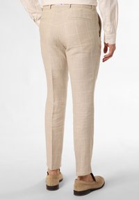 Beige linen trousers with a grid pattern, slim fit, featuring a back pocket; paired with light-colored slip-on shoes.