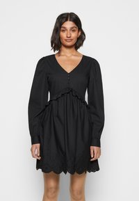 Vestido preto com mangas longas e bufantes, decote em V, frente com botões, cintura com pregas e bainha em renda recortada. Material em mistura de algodão.