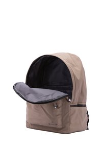 Sac à dos en tissu beige avec un dessus arrondi, compartiment grand ouvert, doublure intérieure grise et un branding discret à l'avant. Les sangles ajustables sont visibles.