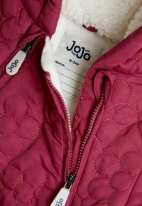 Burgundi színű, steppelt baba dzseki puha fehér bolyhos béléssel, dupla cipzárral és 0-3 hónapos méretet jelző címkével.