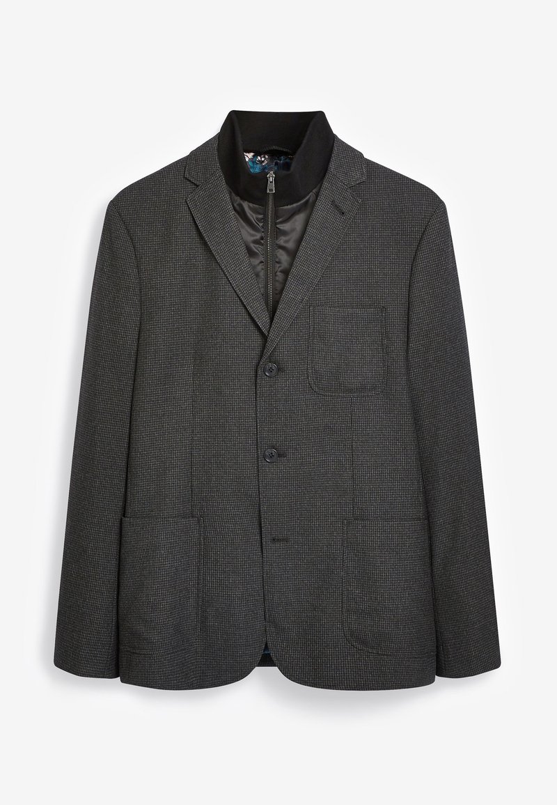 Blazer gris con textura, con cuello de solapa, dos bolsillos frontales y forro interior con cremallera. Cuenta con dos botones y un corte clásico.