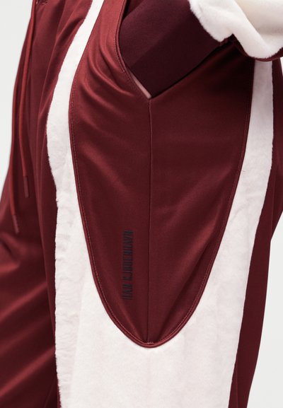 Bordó sport kapucnis pulóver puha fehér polár betéttel, letisztult dizájnnal és márkajelzéssel az oldalán, sima tapintású felülettel.