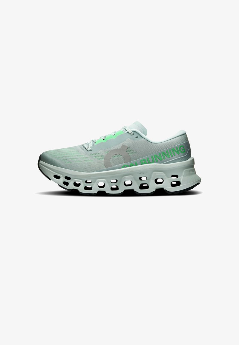 Chaussure de running gris clair et verte avec une semelle évidée et le texte "ON RUNNING" sur le côté, vue de l'extérieur.