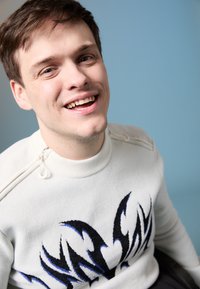 Λευκό πουλόβερ με μπλε και μαύρο αφηρημένο σχέδιο, με φερμουάρ στους ώμους. Το φόντο είναι απαλό μπλε.