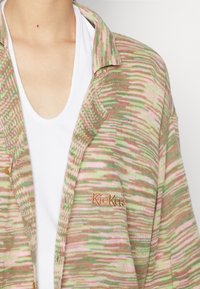 Cardigã tricotado da Kickers em rosa, verde e bege. Apresenta uma textura macia, um colarinho e um logótipo bordado no peito.